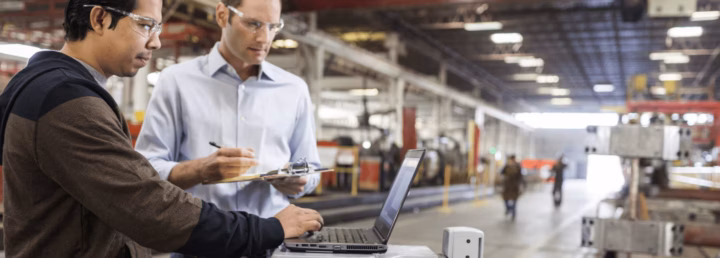 People in a factory looking at a laptop