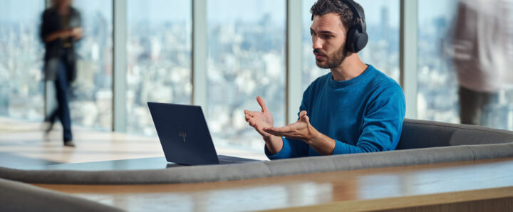 A person gesticulating whilst looking at a laptop