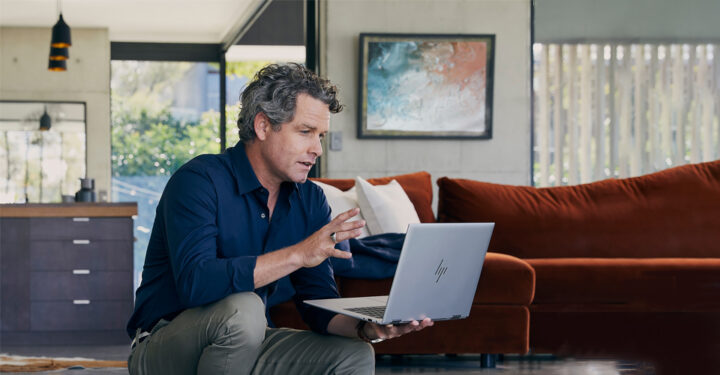 A person sitting down and looking at an HP laptop
