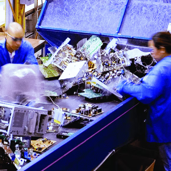 People sorting through a conveyor belt of electronics