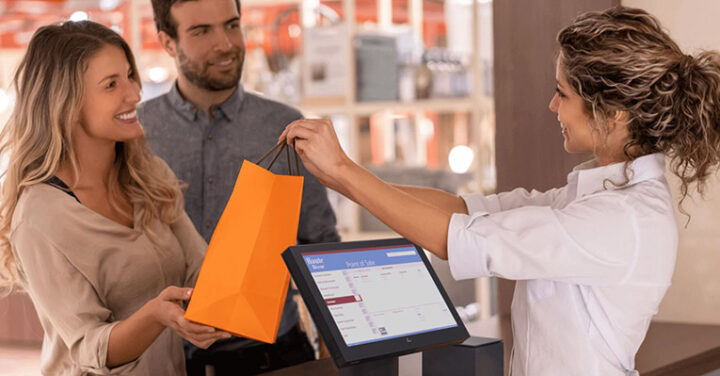 A person handing an orange paper back to a couple